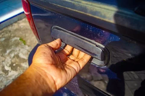 Hand reaching to open tailgate handle on dusty truck highlighting rugged us.. Photos
