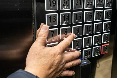 Hand reaching out to elevator panel's braille codes to press button for floor 스톡 사진