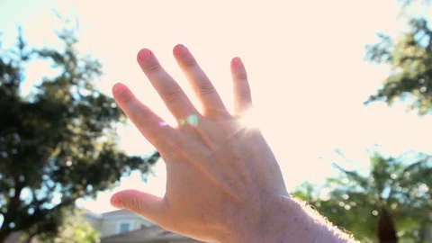 Hand reaching out to the sun in slow motion Stock Footage 129380890
