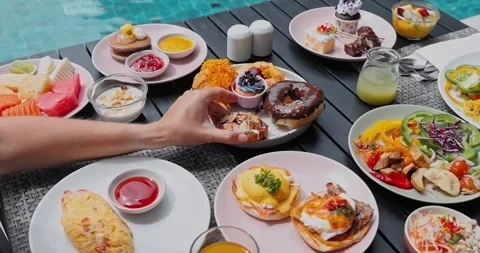 Hand reaching for pastry on table full of breakfast food Stock Footage 335186204