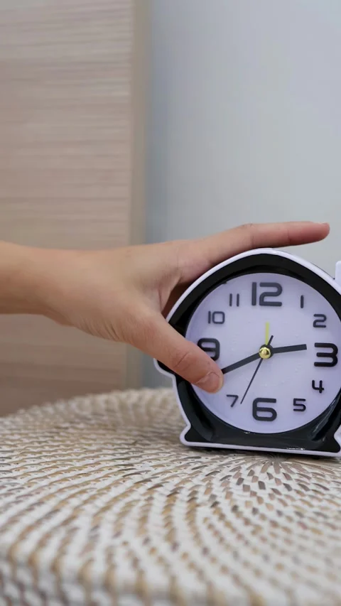 A Hand Reaching to Place an Alarm Clock on a Bedside Table Stock Footage 333604947