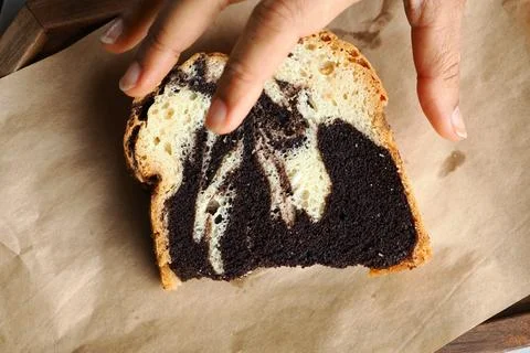 Hand reaching for a slice of marble bread on brown paper Stock Photos