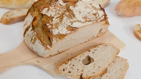 Hand Reaching for Sliced Sourdough Bread on Wooden Board Stock Footage 337281130
