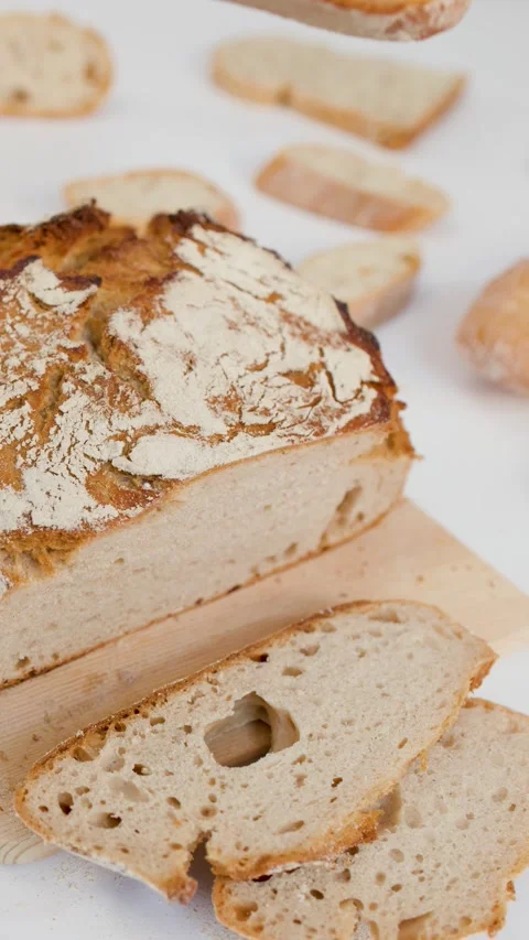 Hand Reaching for Sliced Sourdough Bread on Wooden Board Stock Footage 337875762