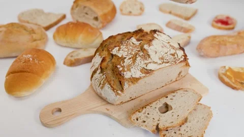 Hand Reaching for Sliced Sourdough Bread on Wooden Board Stock Footage 337876672