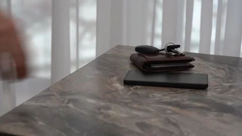 Hand reaching for smartphone and keys on table in daylight Stock Footage 312311973
