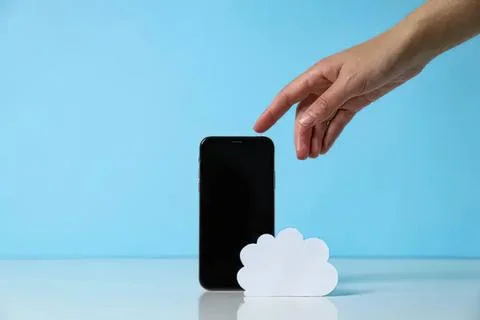Hand reaching for smartphone with cloud icon on blue background Fotos Stock