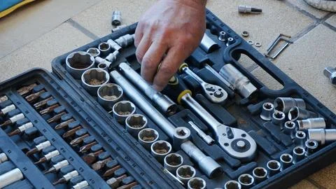 Hand reaching for a socket wrench in a well-organized tool kit, showcasing .. Stock Photos