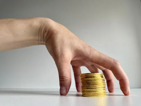 Hand Reaching for Stack of Gold Coins Stock Photos