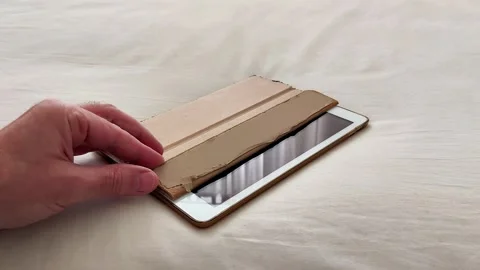 Hand Reaching for Tablet with Brown Cover on Fabric Surface Scene 스톡 동영상 325788878