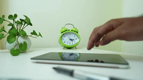 Hand Reaching for Tablet on Desk with Clock and Plant Stock Footage 317737448