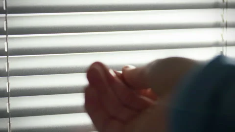 Hand reaching through blinds in a bright room creating a serene atmosphere Stock Footage 304276885