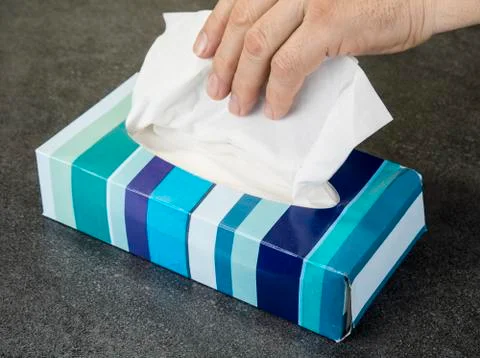 Hand is reaching for the tissue in the box. Stock Photos