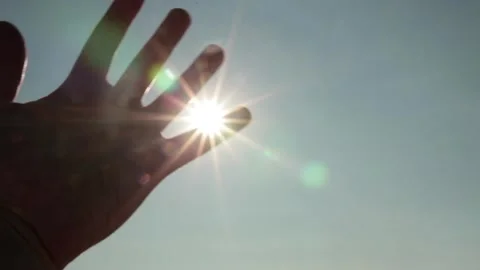 Hand Reaching Toward Bright Sun in Blue Sky Stock Footage 346028449