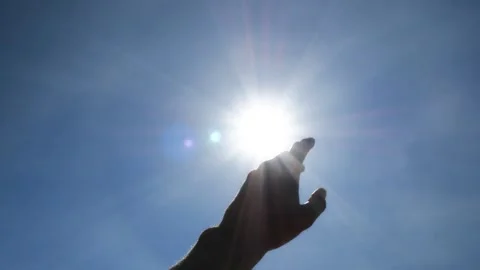 Hand Reaching Toward Bright Sun in Blue Sky Stock Footage 346030519