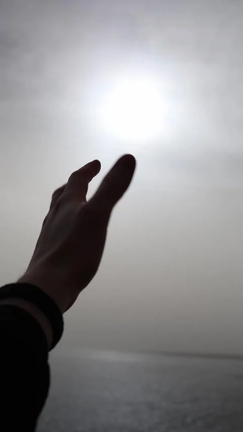 Hand reaching toward a hazy bright sky above the sea Stock Footage 327809857