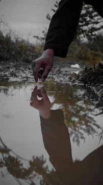 Hand Reaching Towards Puddle Reflection Fotos Stock
