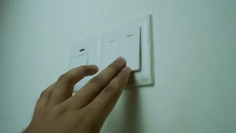 Hand reaching to turn off a light switch on a wall Stock Footage 317737334
