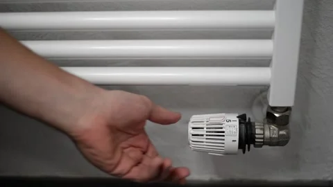 Hand reaching in turning off dial on wall mounted heating element Video stock 204696235