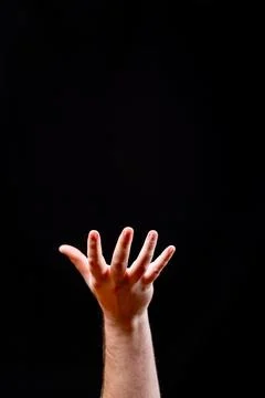 Hand Reaching Upwards on a Solid Black Background 写真素材