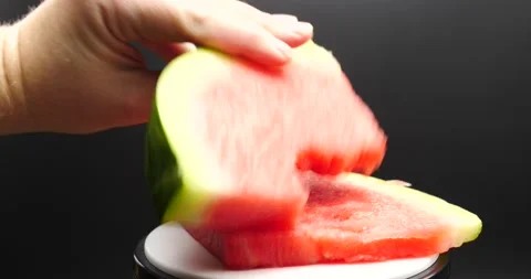 Hand reaching for watermelon close up turning on table isolated on black Stock Footage 205330510