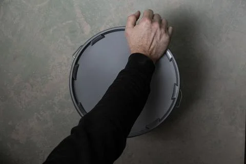 Hand ready to open plaster or filler bucket on concrete floor Stock Photos