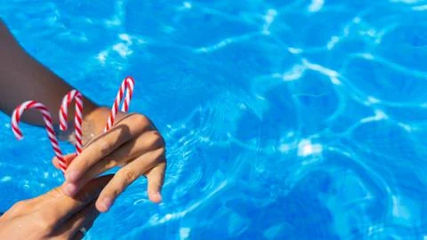 Hand with red candy cane. blue water background. New Year and Christmas on po Stock Photos