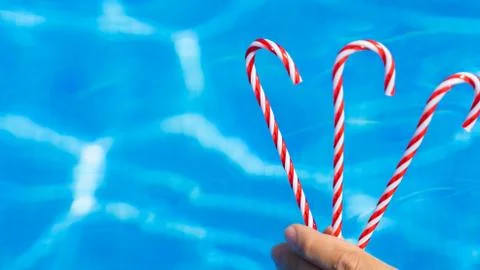 Hand with red candy cane. blue water background. New Year and Christmas on po Stock Photos