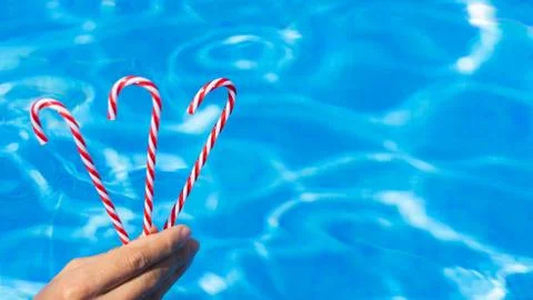 Hand with red candy cane. blue water background. New Year and Christmas on po Stock Photos
