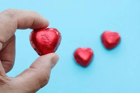 Hand with red candy in the shape of a heart. Stock Photos