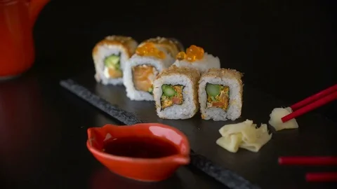 Hand with red chopsticks taking roll sushi from dark plate Stock Footage 69749665