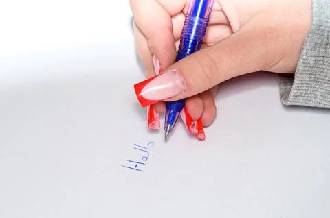 Hand with red nails writing 'Hallo' with blue pen on white paper Stock Photos