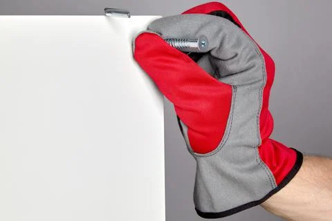 A hand in a red protective glove inserts a confirmation into a hole in a furn Foto stock