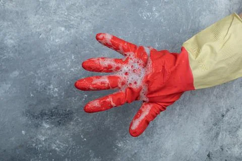 Hand in red protective gloves on marble background Stock Photos