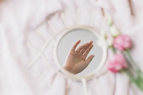 Hand reflected in mirror on background of soft fabric with eustoma flowers,.. Stock Photos