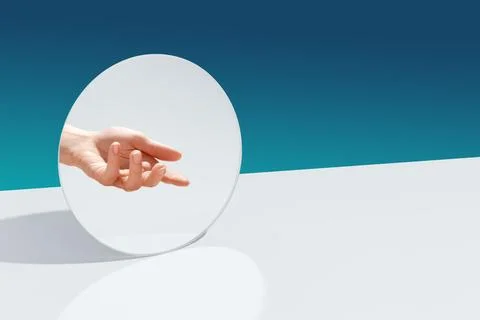 A hand in the reflection of a mirror reaches for an object. Stock Photos