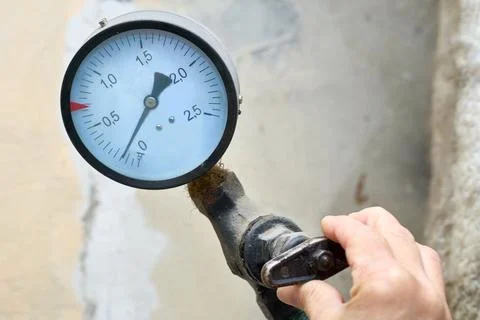 Hand regulating the water supply.Pressure sensor in basement Stockfoto's