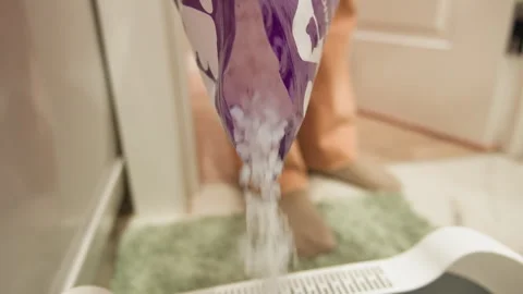 Hand releasing white granules from patterned cloth into bathroom space beside Stock Footage 343543379