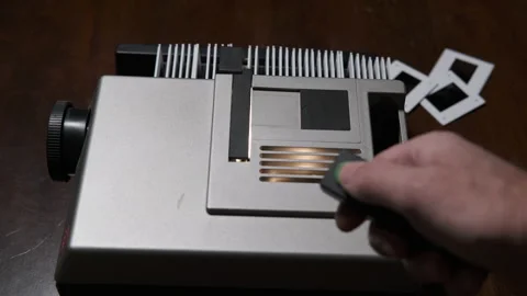 Hand with a remote control of a slide projector in operation to project slides Stock Footage 170727429