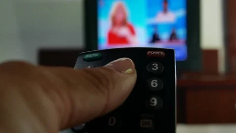 A hand with a remote control switches channels on the TV. Stock Footage 281720009