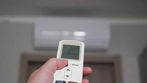 Hand with remote control turns on white air conditioner Stock Footage 198805831