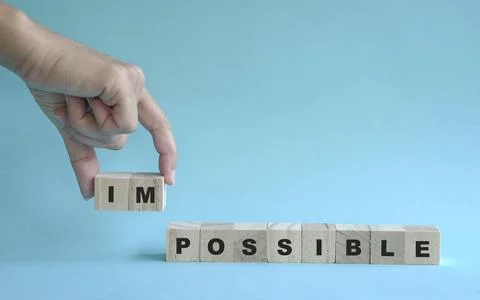 Hand remove wooden cube with word Impossible to Possible. Stock Photos