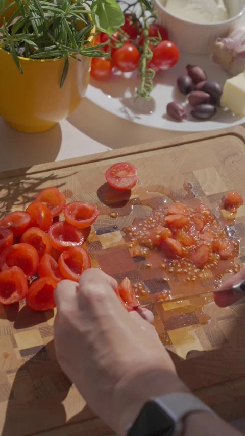 Hand removes pulp from cherry tomatoes with knife on board Stock Footage 337657850
