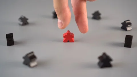 The hand removes the red figure from the environment of black figures Stock Footage 113969775