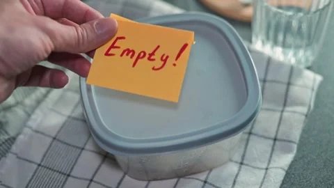 A hand removes a sticky note reading 'Empty' from a container in a kitchen. The Stock Footage 339096793