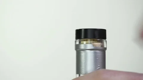 Hand removing and reinserting the cap on a liquor bottle with a silver foil. Stock Footage 77602293