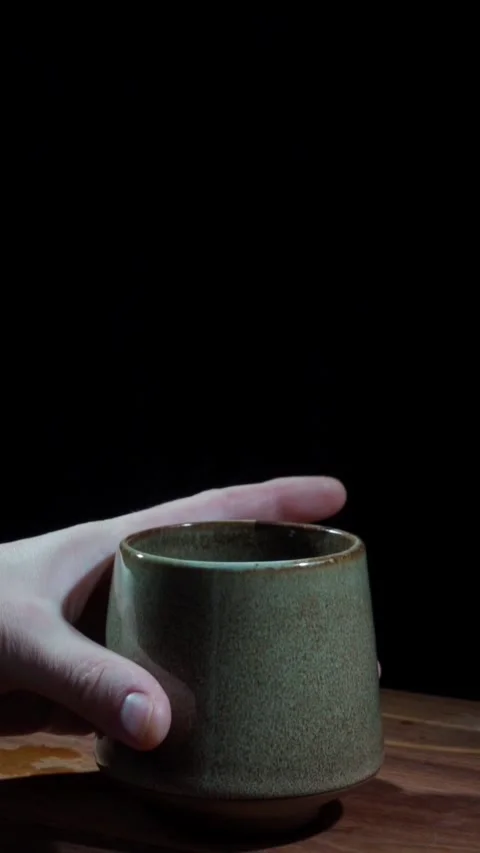 Hand removing ceramic cup from table dark background real time vertical Stock Footage 324762240