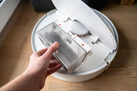 Hand removing dust-filled container from open robot vacuum for cleaning Stock Photos