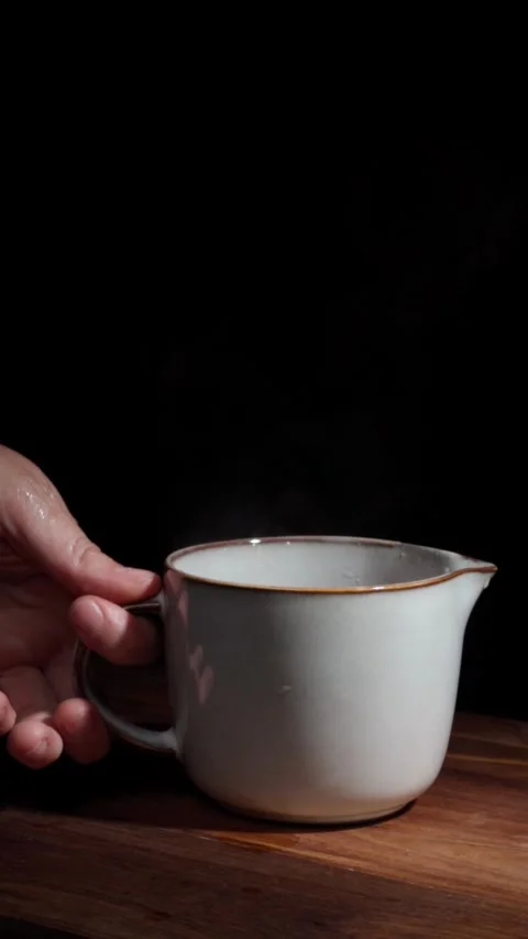 Hand removing hot tea cup steam black background vertical Stock Footage 324761483