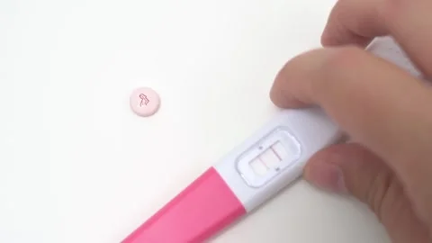 Hand Removing Positive Pregnancy Test leaving Pink Prenatal Pill Stock Footage 340428116
